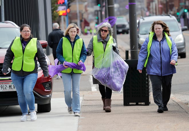 Rachel Schley (from left) of Chippewa Falls, Amanda Pfeiffer of Cadott, Wendy Kopp of Chippewa Falls and Susan Littfin join to hang purple ribbons downtown as officials investigate the homicide of Iliana "Lily" Peters, 10, in Chippewa Falls on Tuesday.