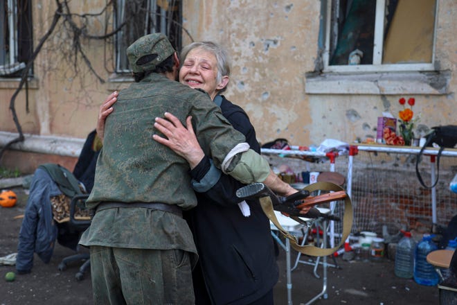 A woman embraces a serviceman of the self-proclaimed Donetsk People's Republic militia near a damaged apartment building in an area controlled by Russian-backed separatist forces in Mariupol, Ukraine, on April 26, 2022.